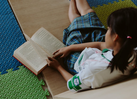 Menina com um livro em mãos representa a ação Descobrindo o Prazer de Ler