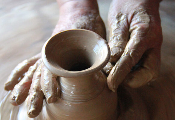 foto mostra mão de uma pessoa em torno de cerâmica